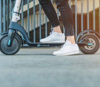 Close up on woman legs feet standing on the electric kick scooter